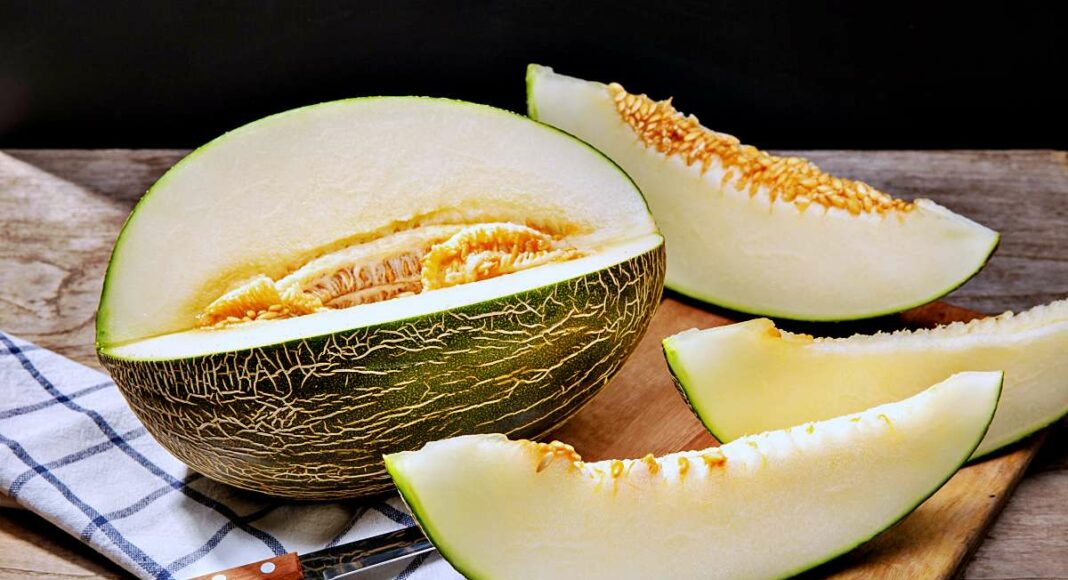 Fresh Muskmelon with slices on wooden table